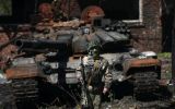 Soldado ucraniano em frente a tanque russo destruído em Kharkiv