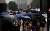 Pedestres se protegem da chuva durante temporal em São Paulo